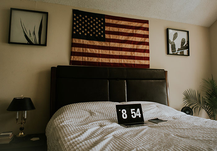 Bedroom wall decor idea featuring a U.S.A. flag above bed with modern black and white framed artwork on each side.