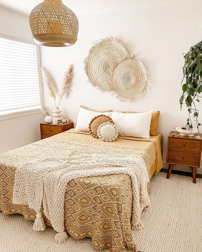 Boho style bedroom with neutral tones, textured blankets, round pillows, and woven wall decor for bedroom wall decor ideas.