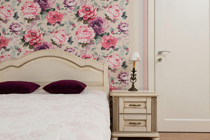 Floral wallpaper behind vintage bed and nightstand creating cool and inspiring bedroom wall decor ideas.
