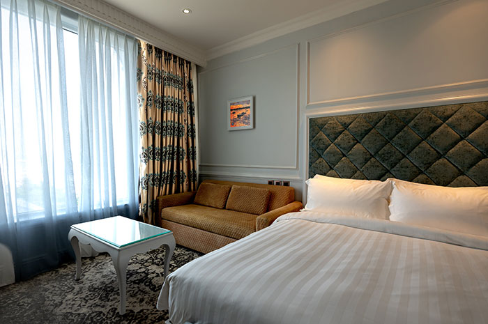 Bright bedroom interior featuring a white bed near a brown couch and table, showcasing stylish bedroom wall decor ideas.