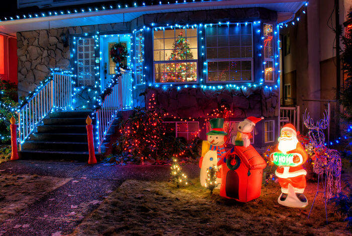 Affordable Christmas decor featuring illuminated snowman, Santa Claus, and festive lights adorning a house and yard at night.