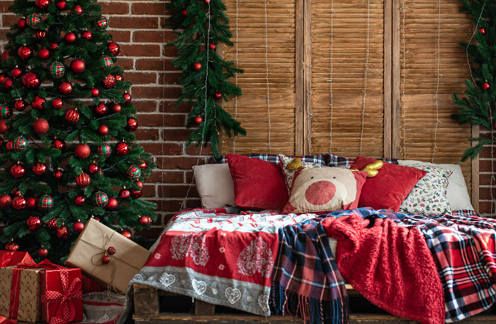 Cozy bed with festive covers and pillows near decorated Christmas tree showcasing affordable Christmas decor ideas.