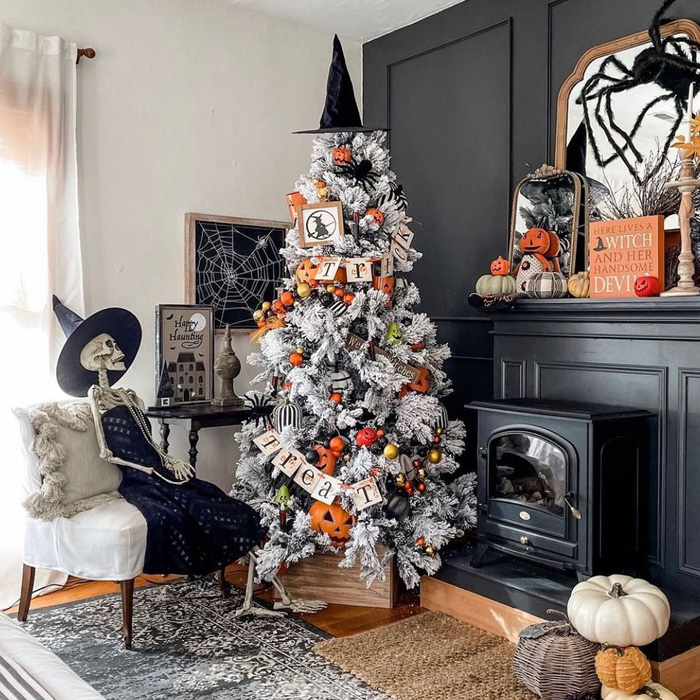 Halloween decorated Christmas tree with spooky ornaments next to skeleton and fireplace for magical Christmas tree decorations.