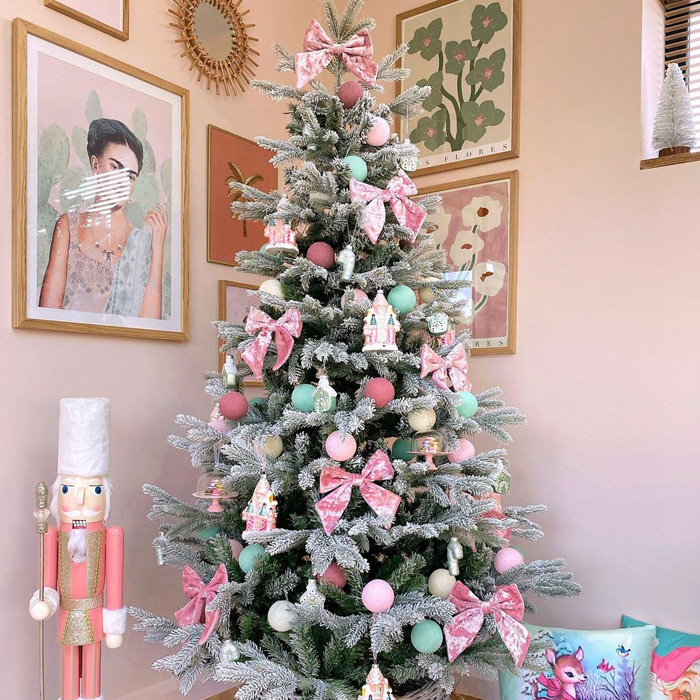 Christmas tree decorated with pink bows, pastel ornaments, and festive village-themed decorations for magical Christmas tree ideas.