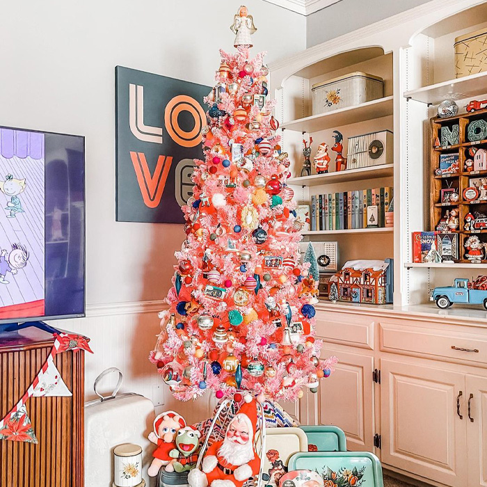 Pink Christmas tree decorated with colorful ornaments and toys placed under it for magical Christmas tree decorations.