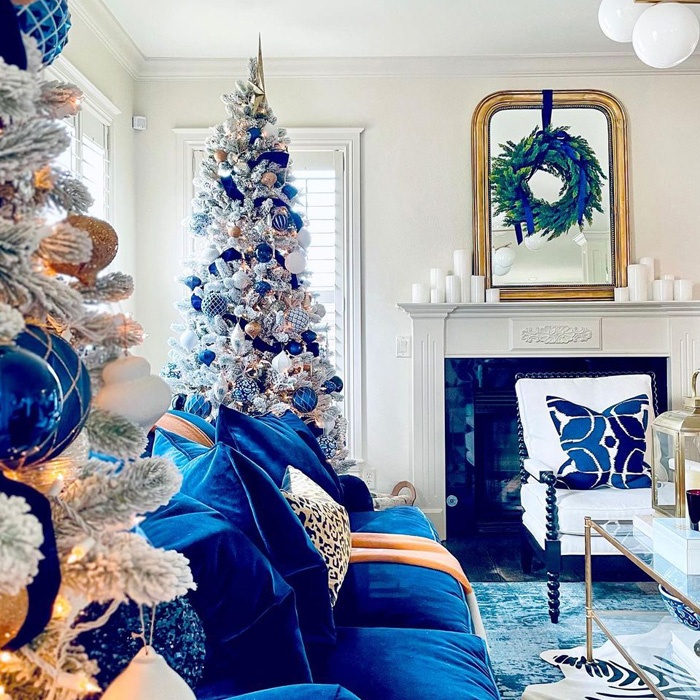 Silver Christmas tree decorated with blue ornaments beside a blue couch in a cozy living room for Christmas tree decorations ideas.