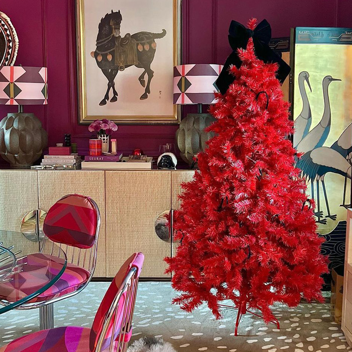 Red Christmas tree decorated with a large black bow, showcasing unique Christmas tree decorations and ideas for jolly celebrations.
