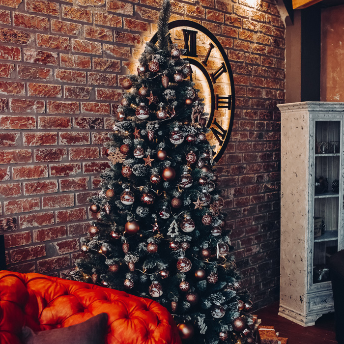 Decorated Christmas tree with magical decorations next to a brick wall and red sofa for festive celebrations