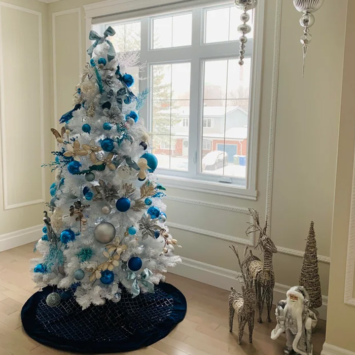 White Christmas tree decorated with blue ornaments and ribbons, showcasing magical Christmas tree decorations and ideas.