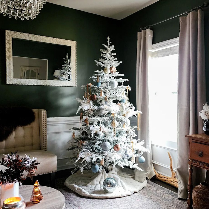 Flocked Christmas tree decorated with ornaments in a cozy green room showcasing magical Christmas tree decorations.