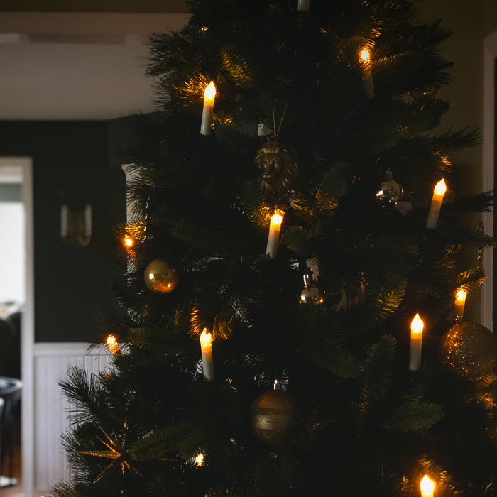 Christmas tree decorated with glowing no-flame candle ornaments and gold baubles for magical Christmas tree decorations.