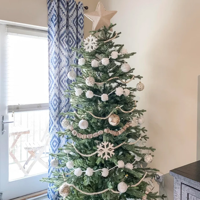Decorated Christmas tree with white ornaments, garlands, and a star topper, showcasing magical Christmas tree decorations.