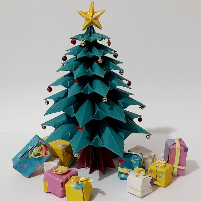 Origami Christmas tree decorated with red and gold beads and presents underneath for magical Christmas tree decorations.