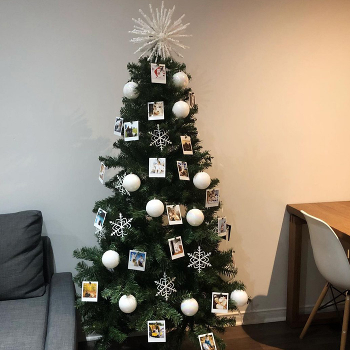 Christmas tree decorated with polaroid photos, white snowflake ornaments, and white baubles for magical Christmas tree decorations.