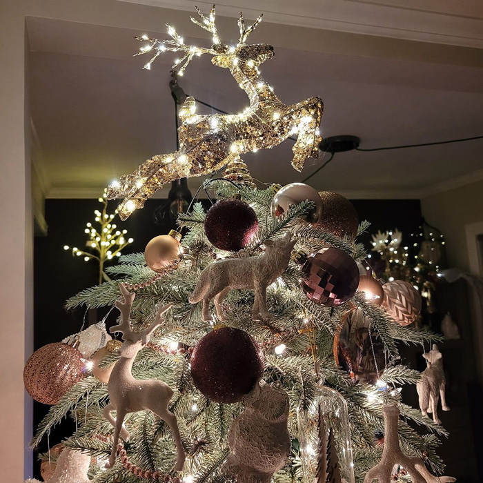 Lighted reindeer tree topper on a Christmas tree surrounded by festive magical Christmas tree decorations and ideas.