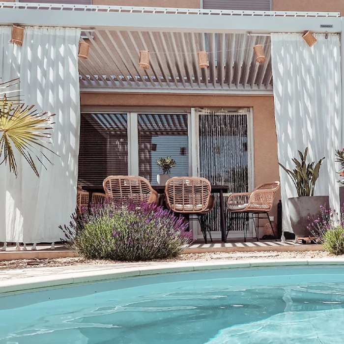 Deck with curtains and wicker chairs by the swimming pool showcasing creative backyard deck ideas for outdoor relaxation.