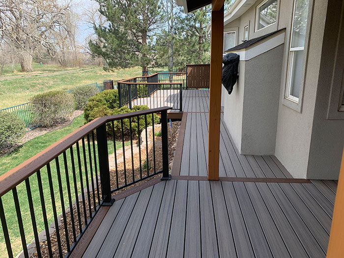 Composite brown and black deck railing design with a spacious outdoor deck overlooking a green backyard area.