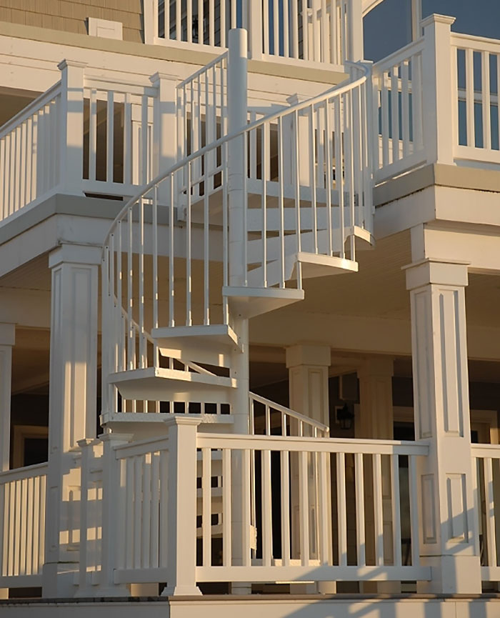 White snaking up and down deck railing design featuring a spiral staircase with vertical balusters and posts.