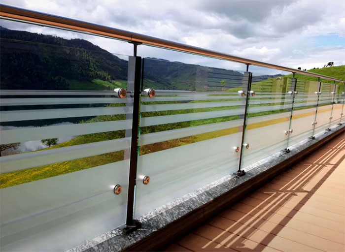 Glass deck railing with etched designs and metal fixtures, enhancing outdoor space with modern deck railing ideas.