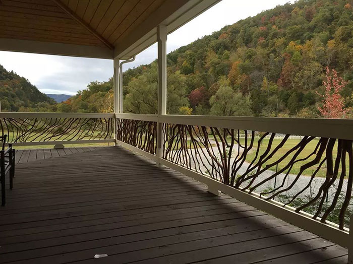 Wooden deck railing design featuring natural branches blending with the forest backdrop for unique exterior appeal