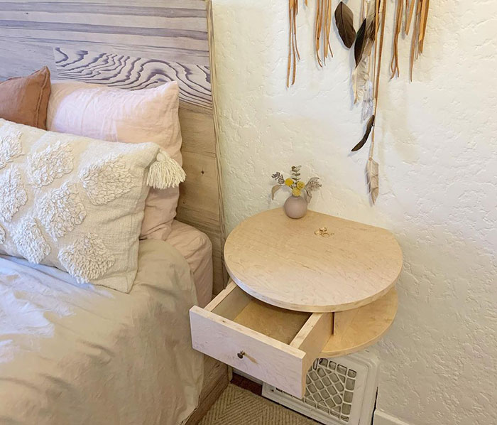 Rounded modern floating nightstand with open drawer beside bed in cozy bedroom design