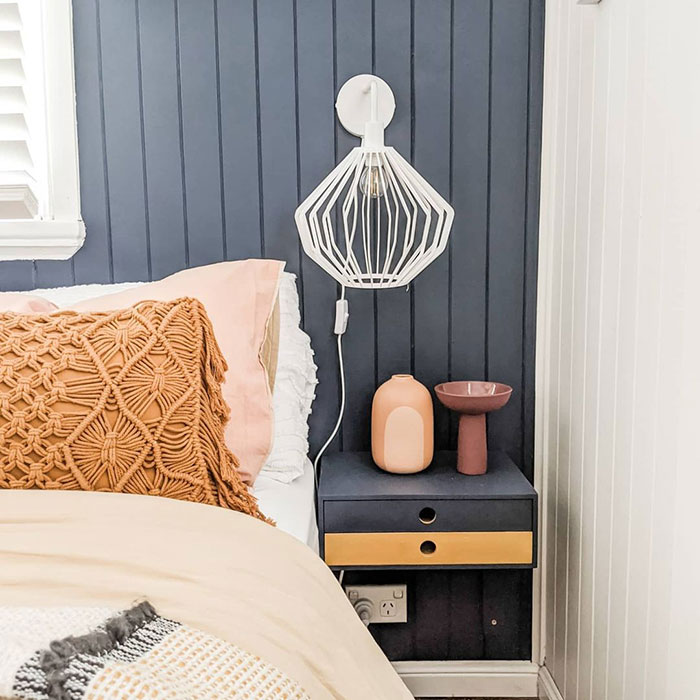 Bamboo modern floating nightstand mounted on dark wood panel wall with decorative vases and a geometric white lamp above.