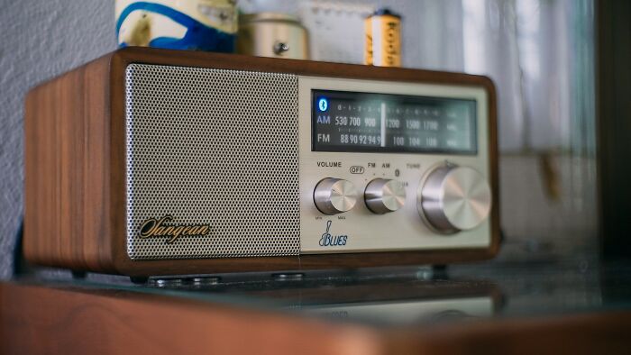 Vintage radio with wooden casing placed on a glass surface, evoking shower thoughts nostalgia.