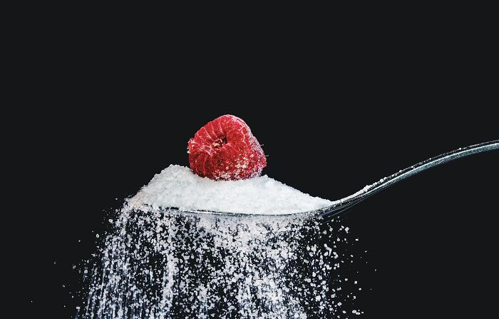 Spoon with sugar and a raspberry, sparking shower thoughts on contrasts and combinations.