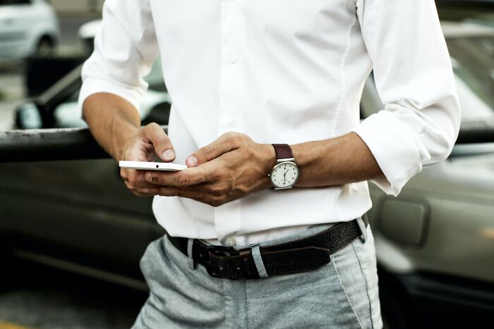 Person in a white shirt holding a smartphone, contemplating shower thoughts questions.
