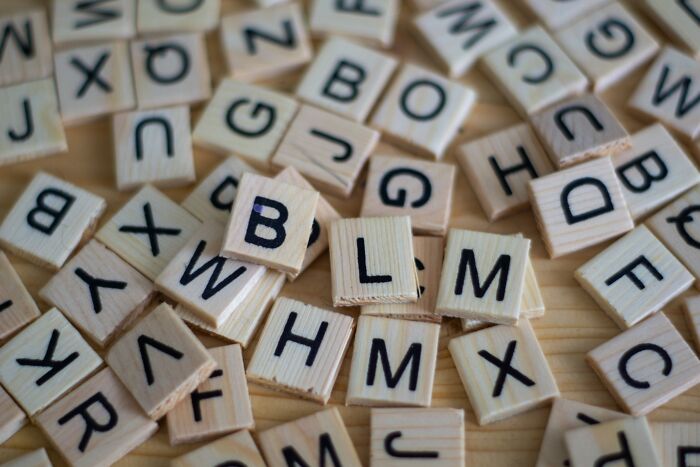 Scattered wooden letter tiles on a table, sparking shower thoughts questions and creativity.