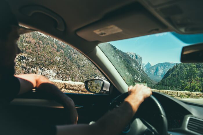 Person driving through scenic mountainous landscape, pondering shower thoughts questions.