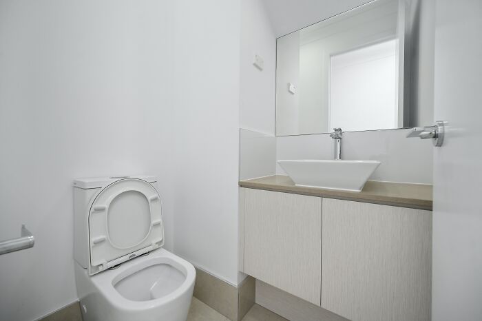 Modern bathroom with white toilet and sink, evoking shower thoughts.