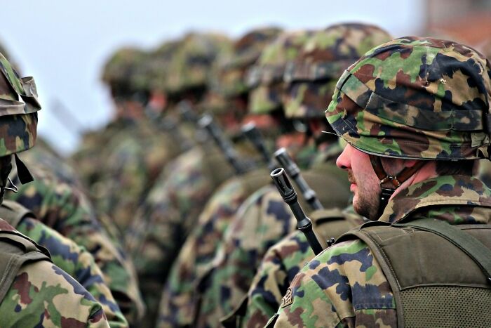 Soldiers in camouflage gear standing in line, showcasing military discipline and shower thoughts questions about conflict.
