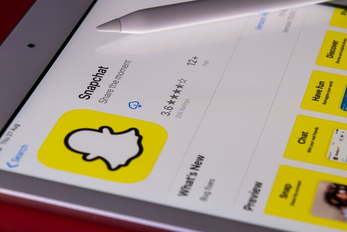 Snapchat app on a tablet screen with a stylus, highlighting its rating and share feature.
