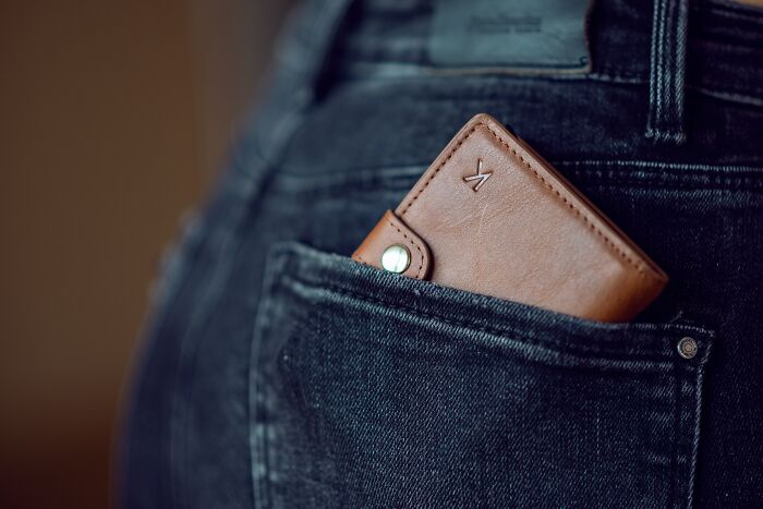 Brown wallet in the back pocket of dark jeans, sparking shower thoughts on everyday items.