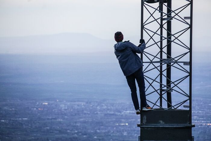 Person climbing tower, pondering shower thoughts questions with a vast landscape in the background.