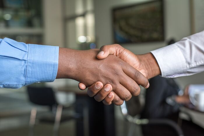 Two people in an office shaking hands, symbolizing a thoughtful agreement.