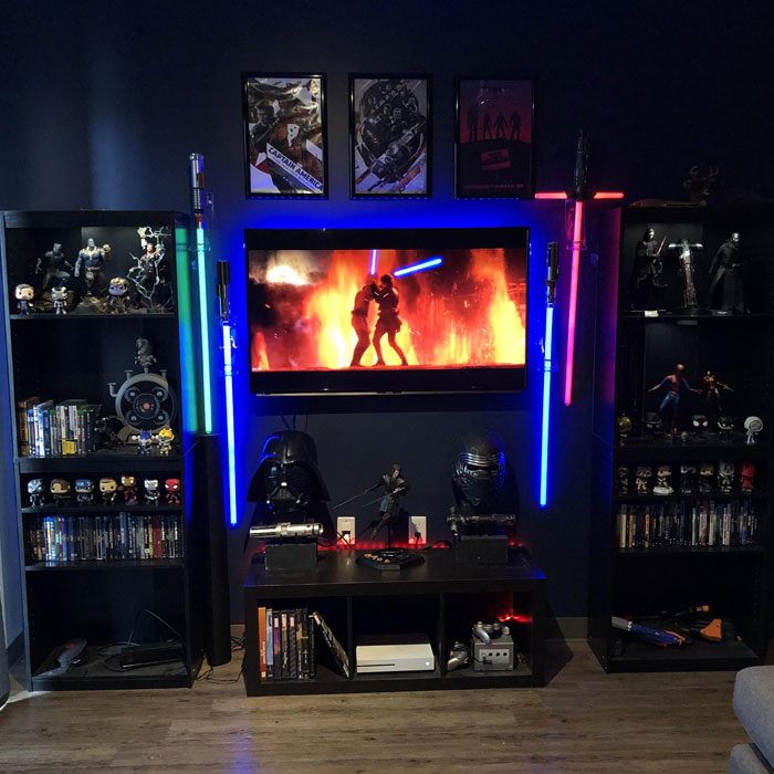 Dark Star Wars themed game room featuring neon lightsabers, movie posters, collectibles, and a mounted flat-screen TV for gaming. Dark Star Wars themed game room featuring neon lightsabers, movie posters, collectibles, and a mounted flat-screen TV for gaming.