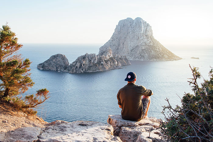 View of Man Sitting on Rock by Sea