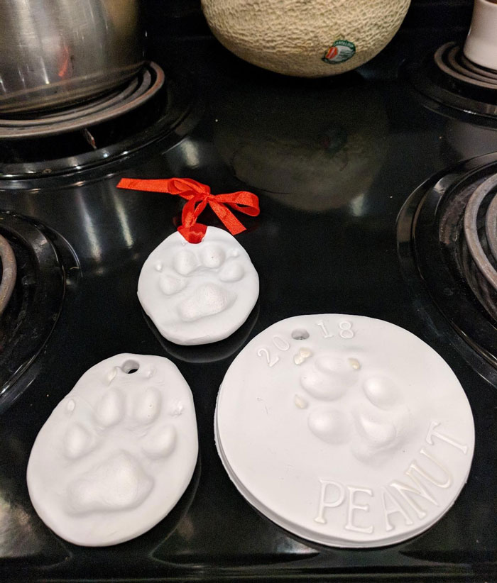 Three handmade white paw print ornaments made from clay, showcasing unique pet paw impressions as gifts for pets.
