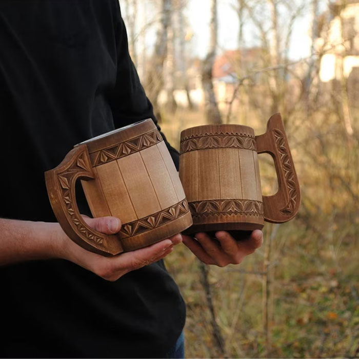 Person holding two carved wooden mugs outdoors, showcasing stylish home bar ideas for a cozy happy hour setting. Person holding two carved wooden mugs outdoors, showcasing stylish home bar ideas for a cozy happy hour setting.