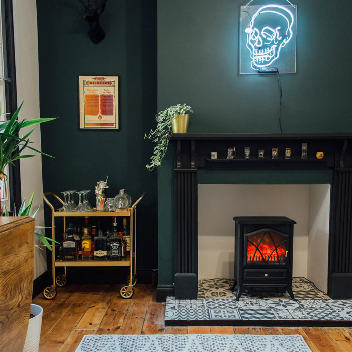 Small golden bar cart with bottles and glasses in cozy corner near fireplace showcasing home bar ideas. Small golden bar cart with bottles and glasses in cozy corner near fireplace showcasing home bar ideas.