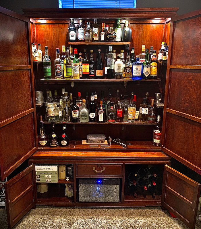 Old brown cabinet filled with various bottles and spirits, showcasing stylish home bar ideas for any hour. Old brown cabinet filled with various bottles and spirits, showcasing stylish home bar ideas for any hour.