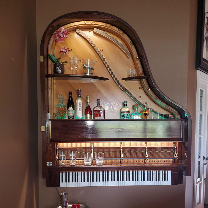 Minimalist home bar idea using a repurposed grand piano with shelves holding bottles and glasses for happy hour. Minimalist home bar idea using a repurposed grand piano with shelves holding bottles and glasses for happy hour.
