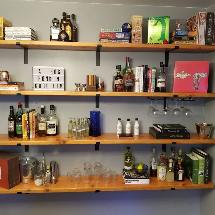 Home bar ideas featuring a stylish shelf with books, liquor bottles, cocktail glasses, and drink mixers. Home bar ideas featuring a stylish shelf with books, liquor bottles, cocktail glasses, and drink mixers.