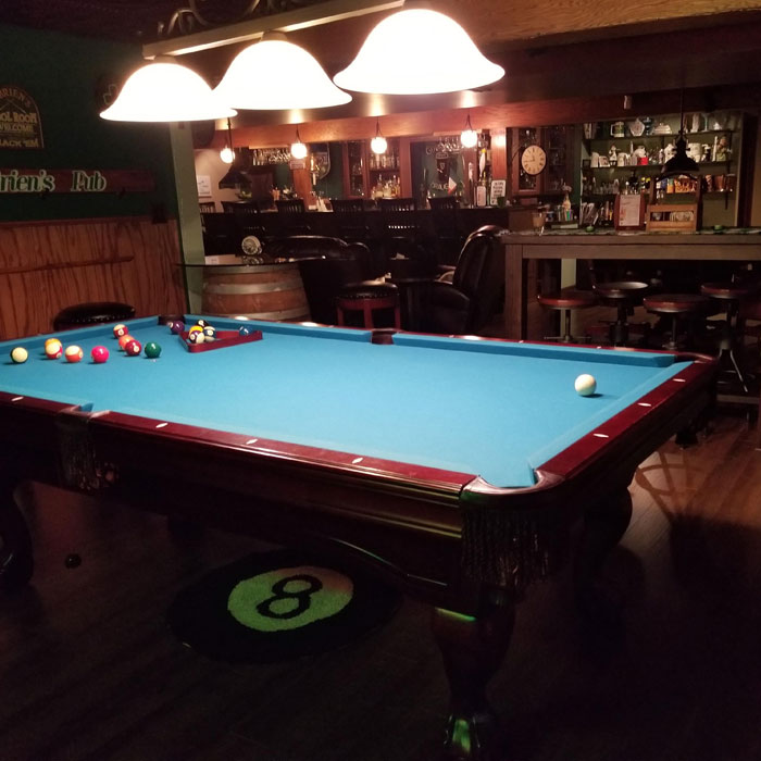 Pool table with blue felt in a cozy wooden home bar illuminated by hanging lights for a stylish happy hour setup Pool table with blue felt in a cozy wooden home bar illuminated by hanging lights for a stylish happy hour setup