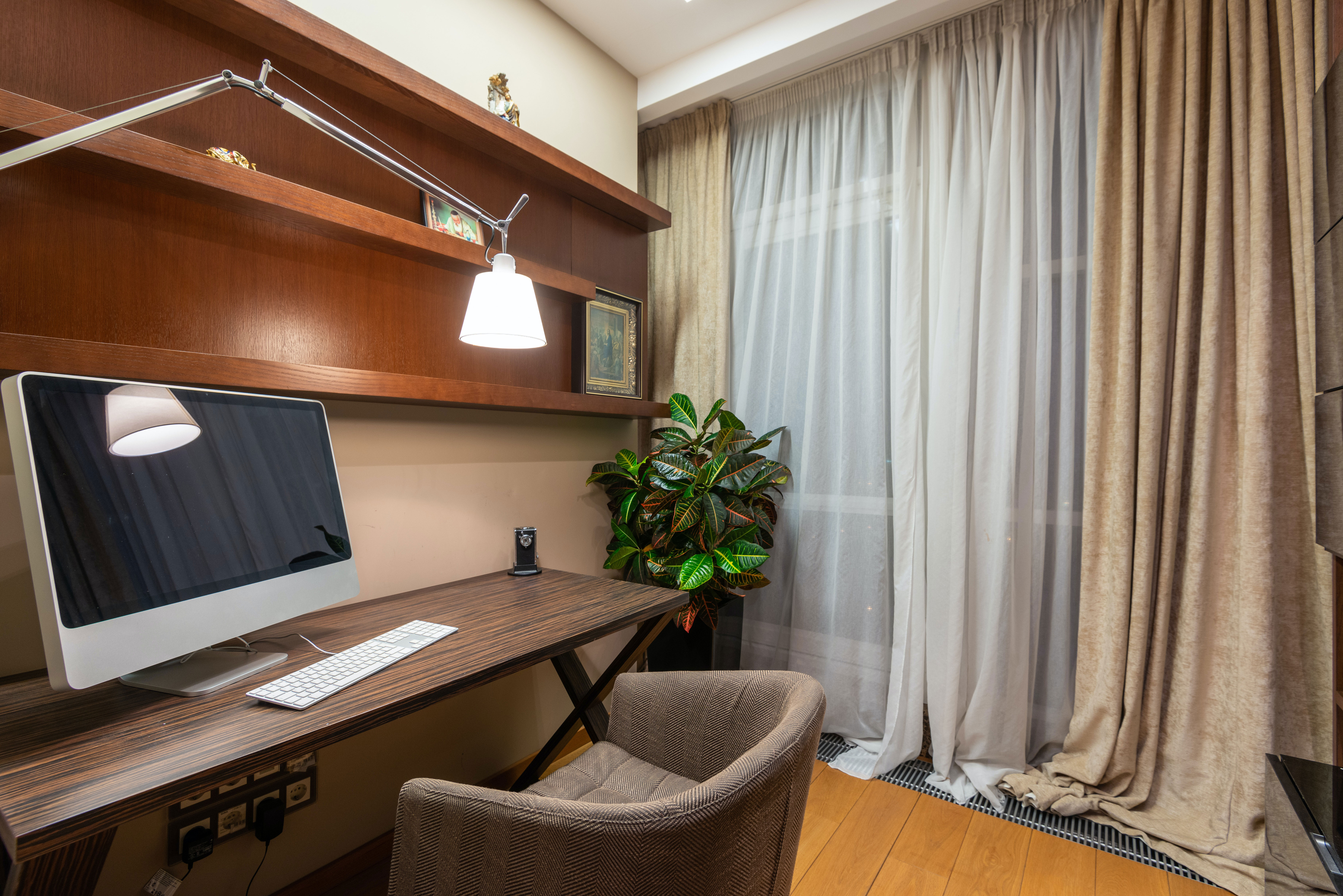 Modern home office setup with a comfortable chair, wooden desk, monitor, and natural light for productive work ideas