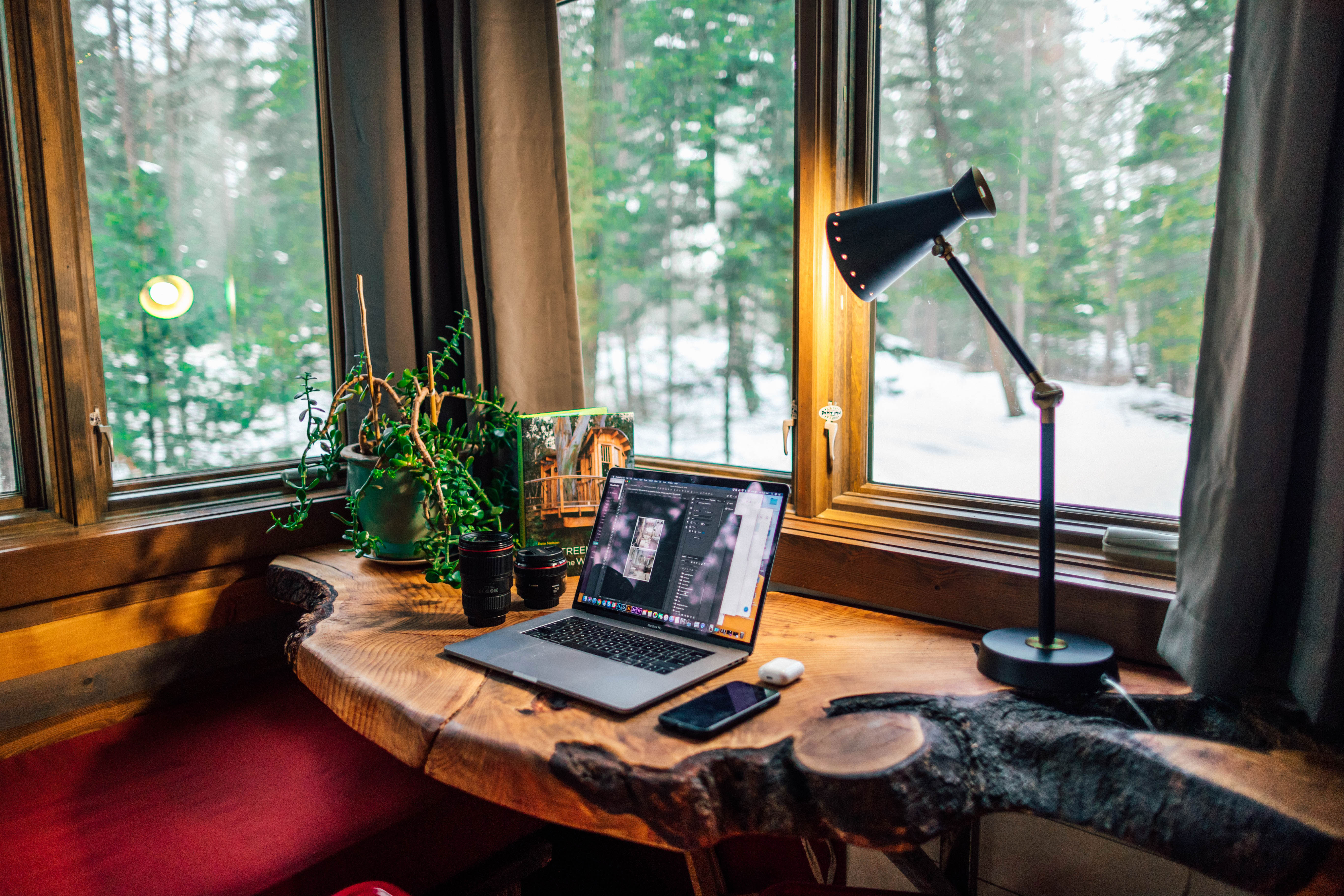 Laptop on a wooden desk near window with forest view, showcasing home office ideas for inspired and productive work process.