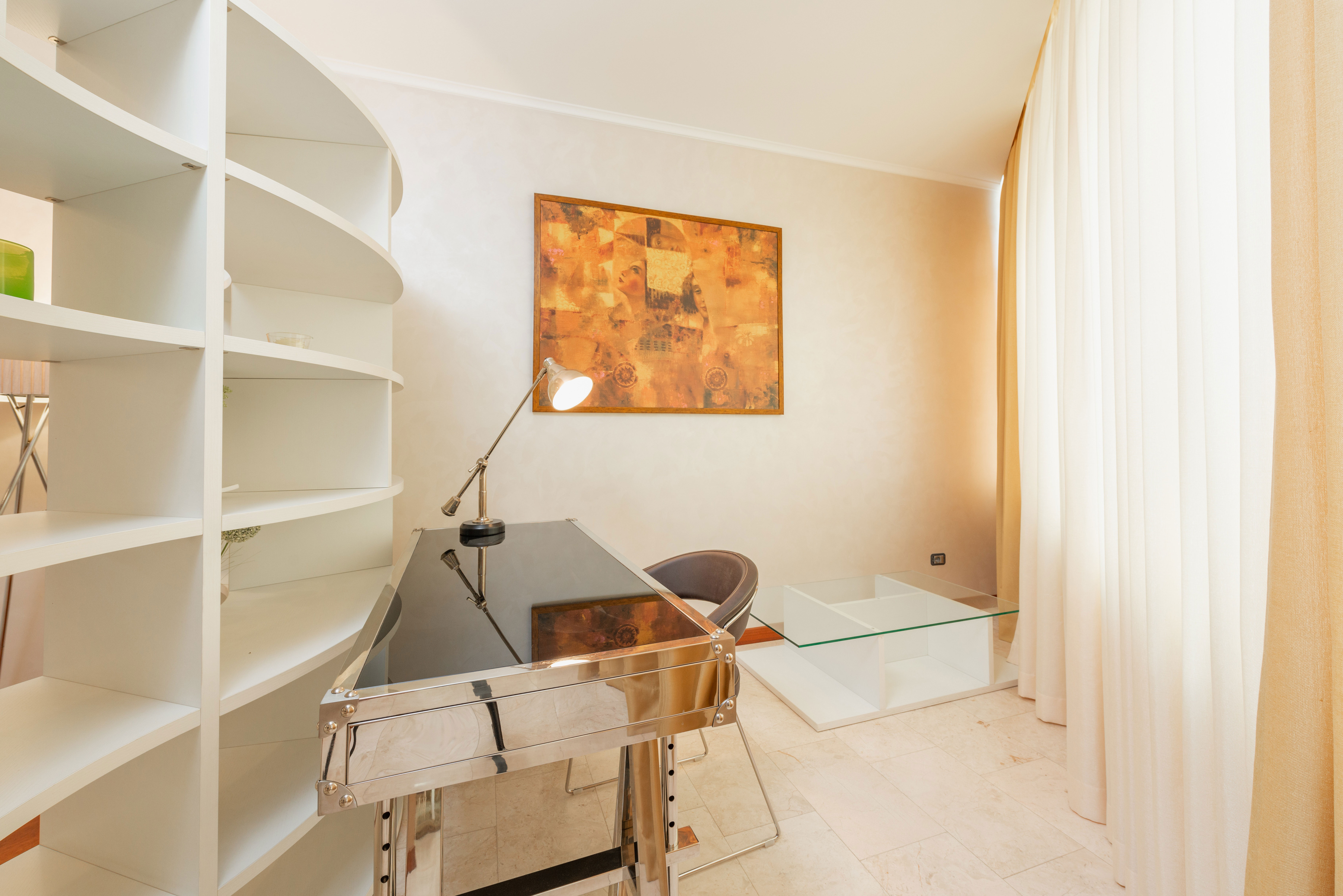 Modern home office ideas featuring a sleek desk, abstract painting, white shelving, and light curtains in a bright apartment.