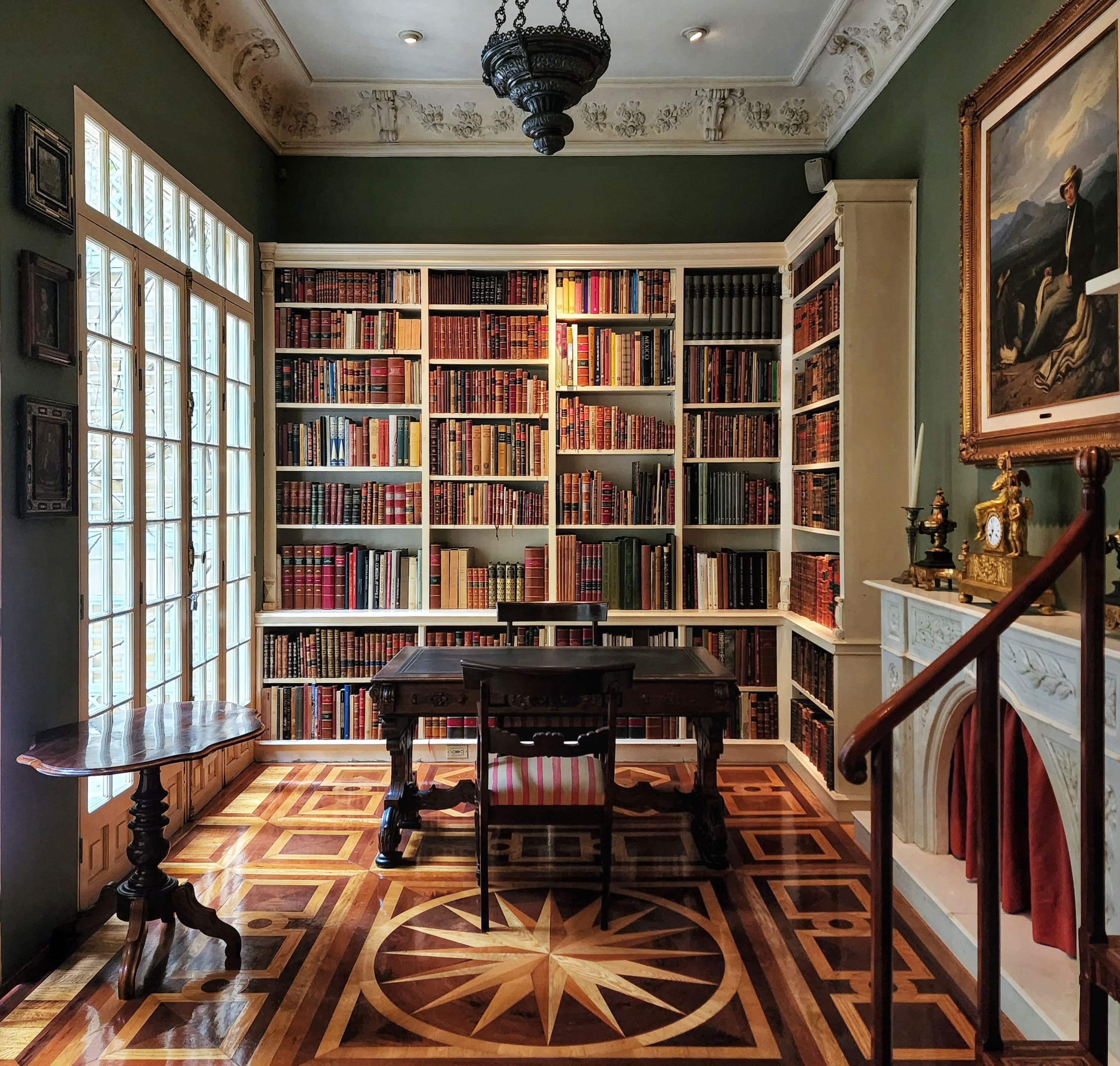 Classic home office with black wooden chairs and table surrounded by bookshelves for a productive work process.